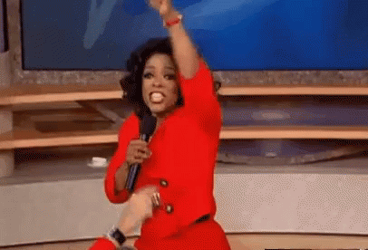 Oprah Winfrey joyfully throwing car keys into the air while audience members cheer